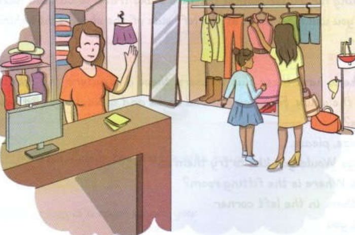 A shopkeeper waving from the counter while a woman and a girl look at clothes on a rack
